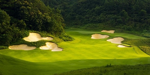 Một sân trong chuỗi Mission Hills Golf Club tại Trung Quốc với đường lăn bóng hẹp và cây rừng là chướng ngại.