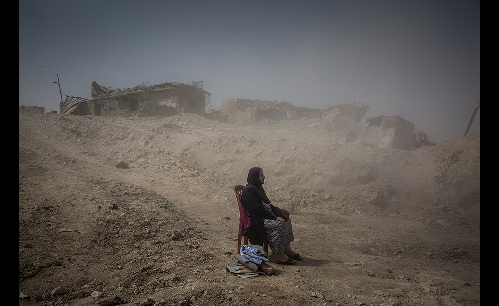 Giải nhất Tin tổng hợp, (hạng mục ảnh bộ) Nhiếp ảnh gia người Ireland Ivor Prickett, làm việc cho tờ New York Times, đã được trao tặng cho tác phẩm về khung cảnh tại chiến trường Musul ở Iraq. Trong ảnh, bà Nadhira Aziz, ngồi cách ngôi nhà bị phá hủy vài mét trong một vụ đánh bom, đang chờ đợi thi thể của thân nhân được đưa ra khỏi đống đổ nát. (Ivor Prickett / The New York Times)