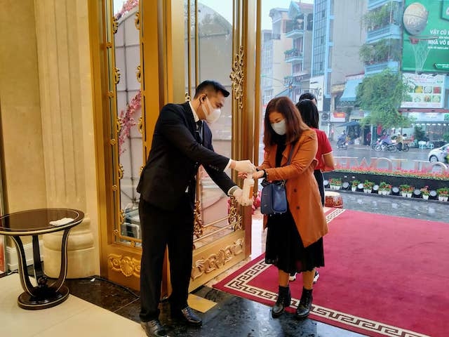 Khách hàng tới mua vàng còn được sát khuẩn tay bằng nước rửa tay khô tại cửa hàng vàng Doji số 5 Lê Duẩn (Hà Nội)