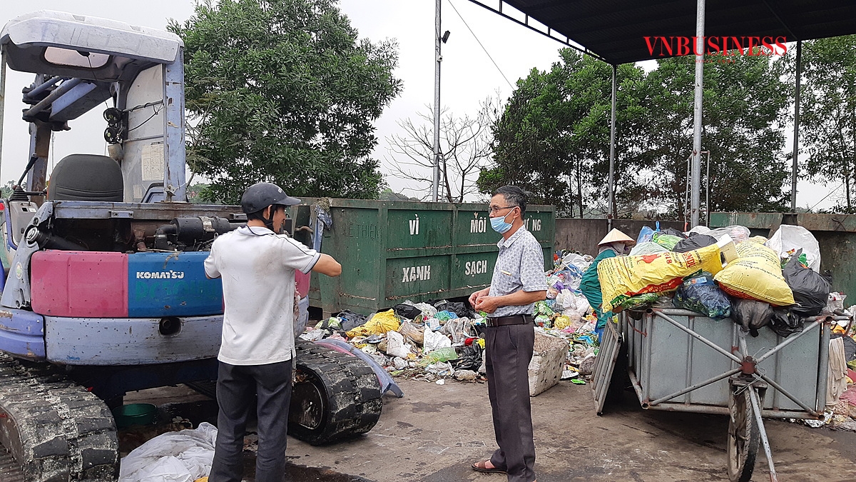 Phó giám đốc HTX, ông Phạm Đức Bê (bên phải) đang chỉ đạo công nhân lái máy xúc chuẩn bị xúc rác vào container