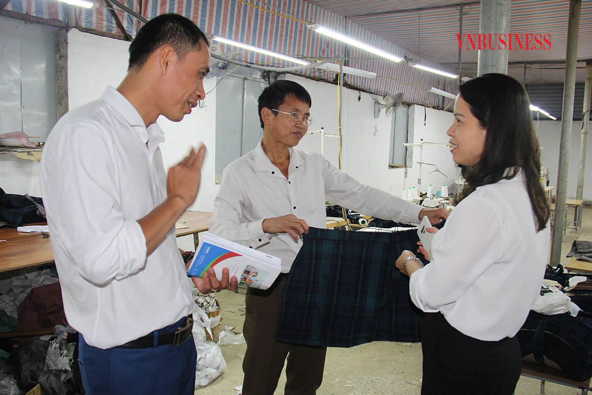 Ông Bùi Đăng Hiệp (giữa) giới thiệu sản phẩm may gia công cho công ty đối tác.