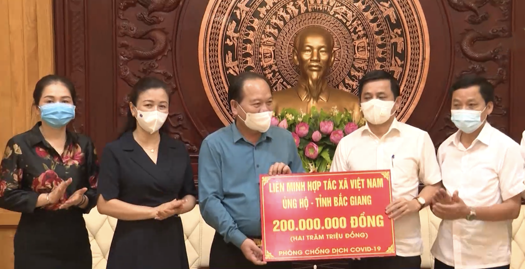 Phó Chủ tịch Liên minh HTX Việt Nam Nguyễn Văn Thịnh (áo trắng đứng giữa) trao số tiền Liên minh HTX Việt Nam ủng hộ tỉnh Bắc Giang.