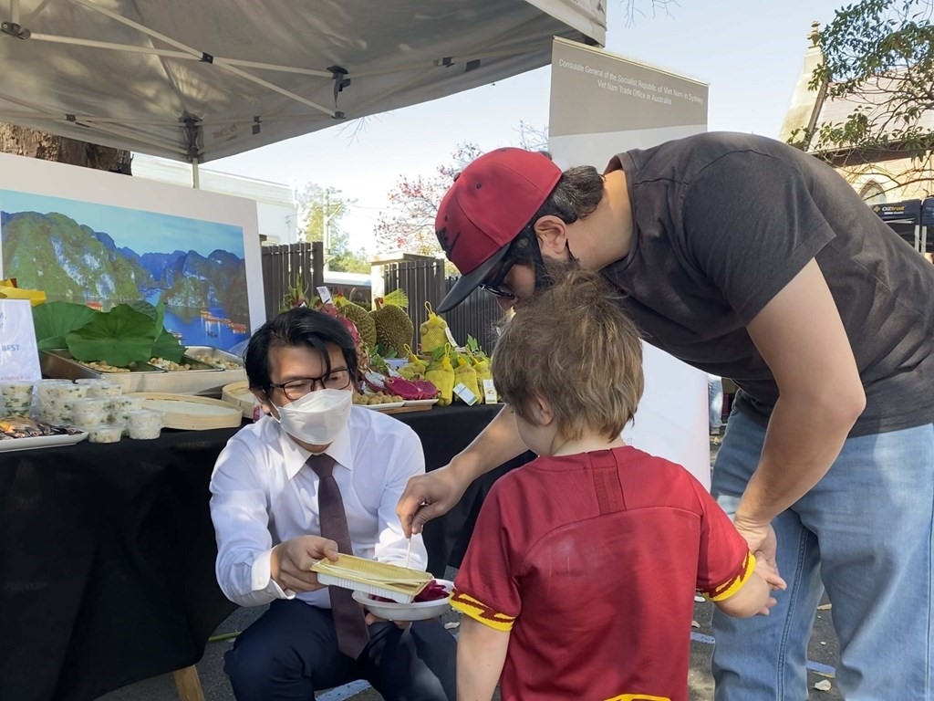 Trưởng cơ quan Thương vụ Việt Nam tại Úc - ông Nguyễn Phú Hoà mời bạn nhỏ dùng thử thanh long.