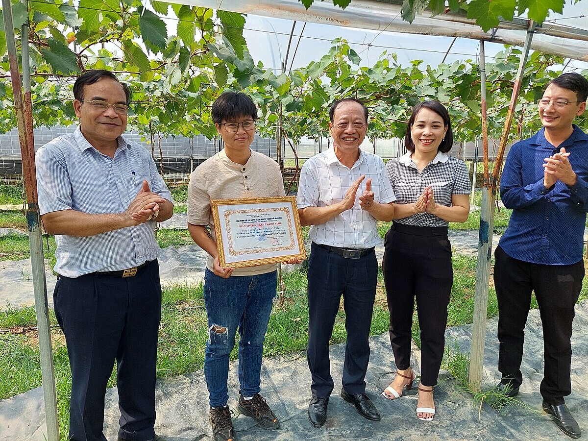 Ông Lương Minh Huệ – Chủ tịch Liên minh HTX và Doanh nghiệp TP Hải Phòng (người mặc áo trắng, đứng giữa) trao Giấy chứng nhận thành viên cho HTX Nông trại Vui Vẻ.