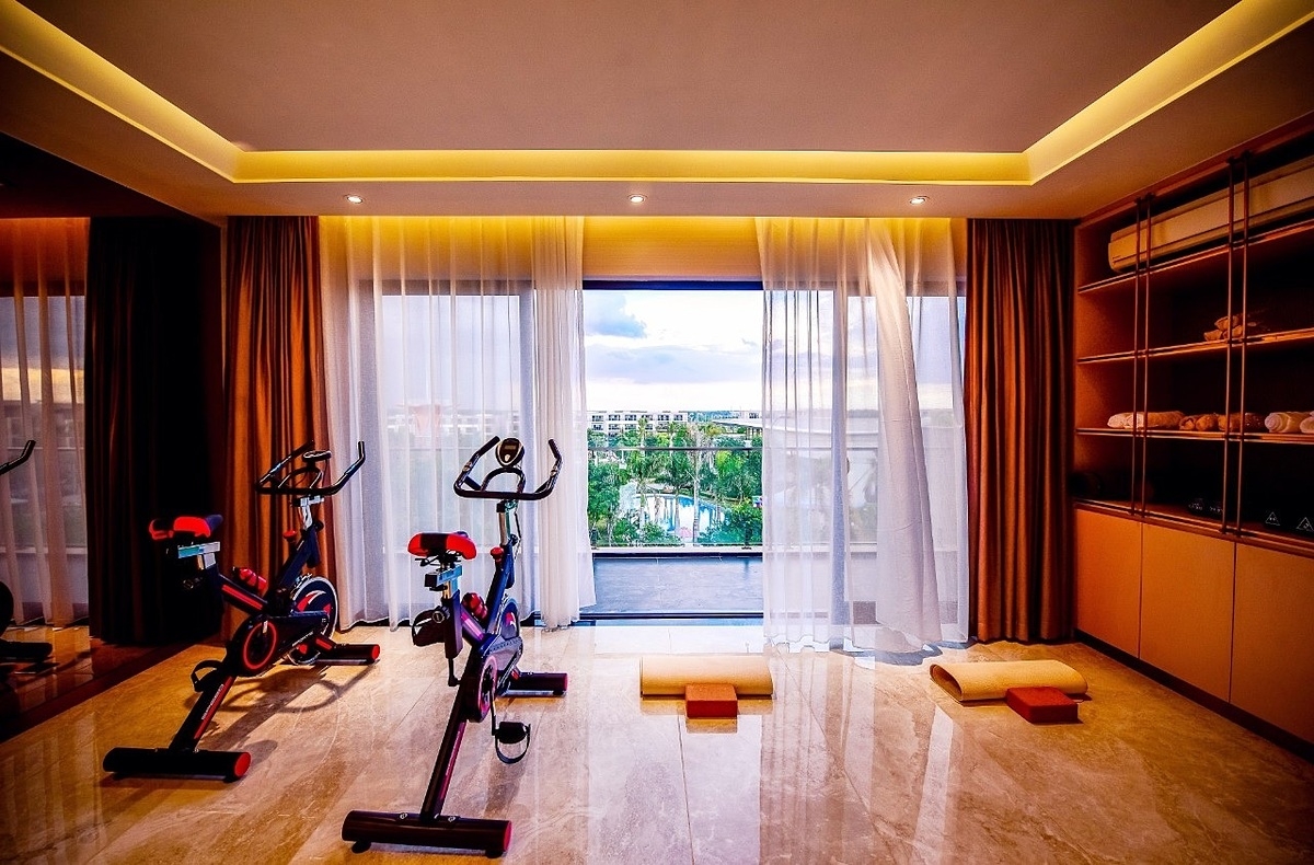 Không gian tập luyện thể thao trong nhà, có hướng nhìn ra công viên trung tâm rợp sắc xanh.