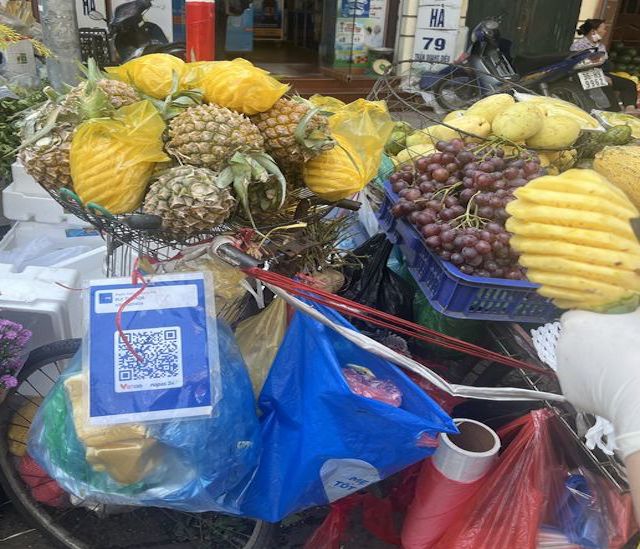 Khách mua quả dứa 10.000 đồng giờ đây chỉ cần quét mã QR để thanh toán thay vì trả tiền mặt.