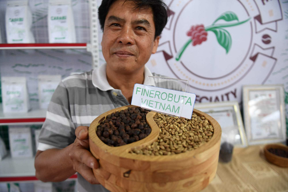 Nông dân Hoàng Mạnh Hùng bên những hạt cà phê thu hoạch từ trang trại của gia đình ở Buôn Ma Thuột. Ảnh: Nhạc Nguyễn/AFP