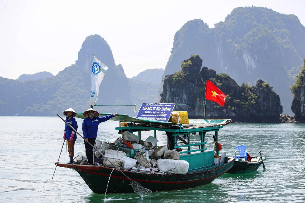 Những người nhặt rác đang vớt bỏ những chiếc phao xốp nổi lềnh bềnh trên Vịnh Hạ Long. Ảnh: AFP