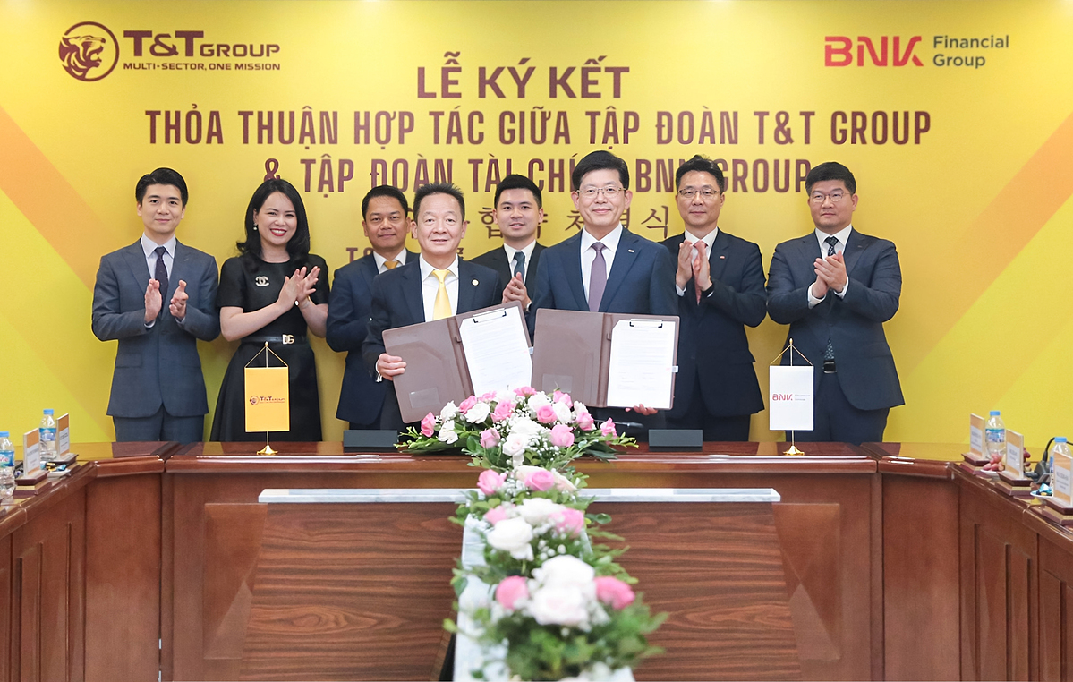 Ông Đỗ Quang Hiển, Chủ tịch UBCL Tập đoàn T&T Group &lpar;bên trái&rpar; và ông Bin Dae-in, Chủ tịch HĐQT kiêm TGĐ Tập đoàn Tài chính BNK &lpar;bên phải&rpar; trao thỏa thuận hợp tác với sự chứng kiến của đại diện lãnh đạo hai Tập đoàn.