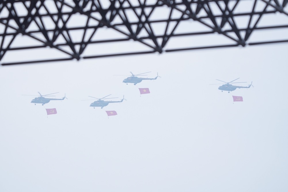 Các biên đội trực thăng vũ trang thuộc Quân chủng Phòng không - Không quân, Quân đội nhân dân Việt Nam mang theo cờ Đảng, cờ Tổ quốc Việt Nam diễu hành tiến qua sân vận động Điện Biên.