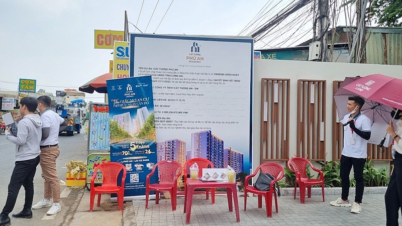 Nhân viên môi giới phát tờ rơi quảng cáo dự án Cát Tường Phú An tại cổng chính dự án.