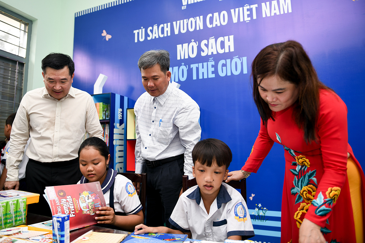 Các em học sinh khám phá tủ sách mới do Vinamilk trao tặng tại thư viện trường .