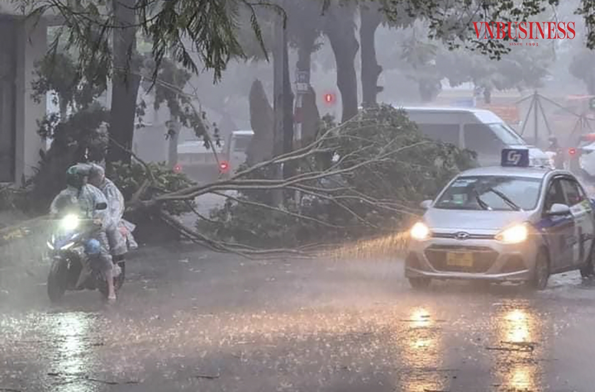 Người dân di chuyển khó khăn dưới cơn mưa lớn, gió giật mạnh, tầm nhìn bị hạn chế.