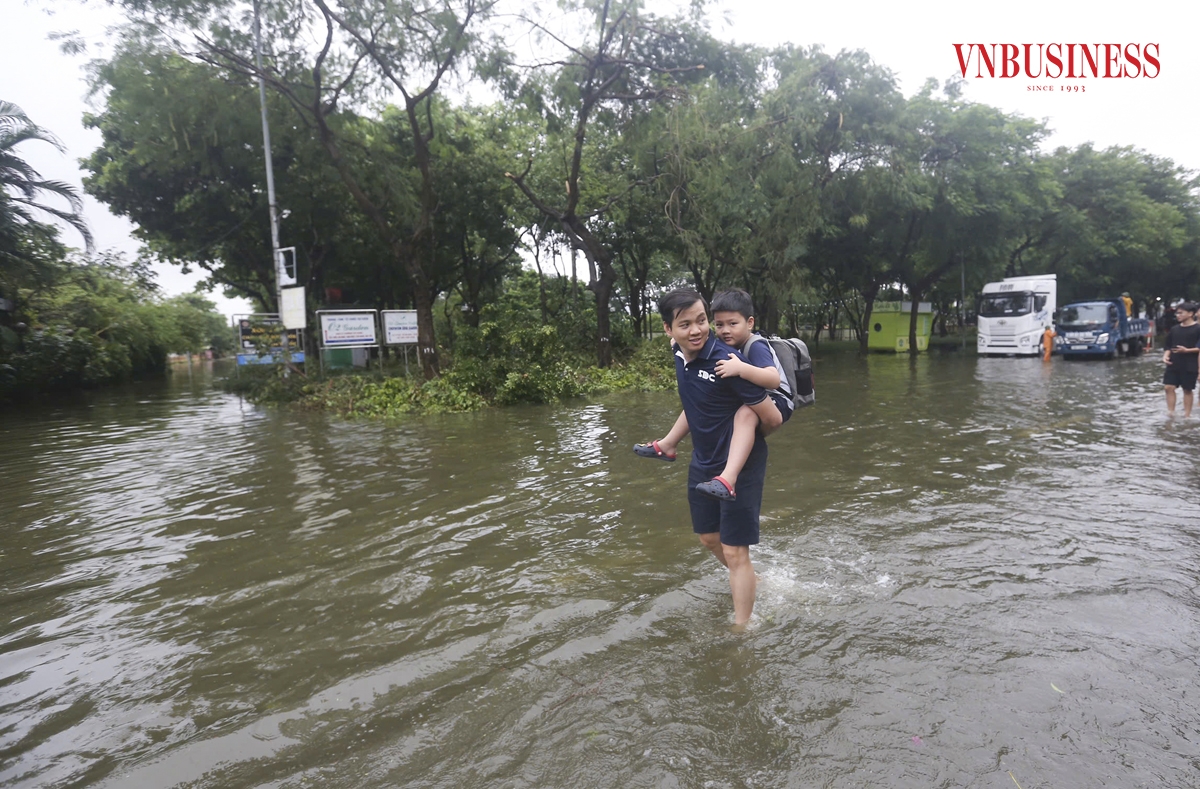 Phụ huynh phải cõng các em nhỏ, vượt qua khu vực úng ngập để kịp tới trường.