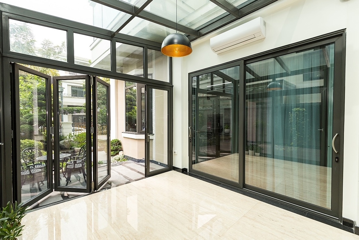 Một góc không gian biệt thự hiện đại lắp đặt đồng bộ mái kính, vách nhôm kính, cửa nhôm gấp trượt dọc, cửa nhôm mở trượt cao cấp Eurowindow.