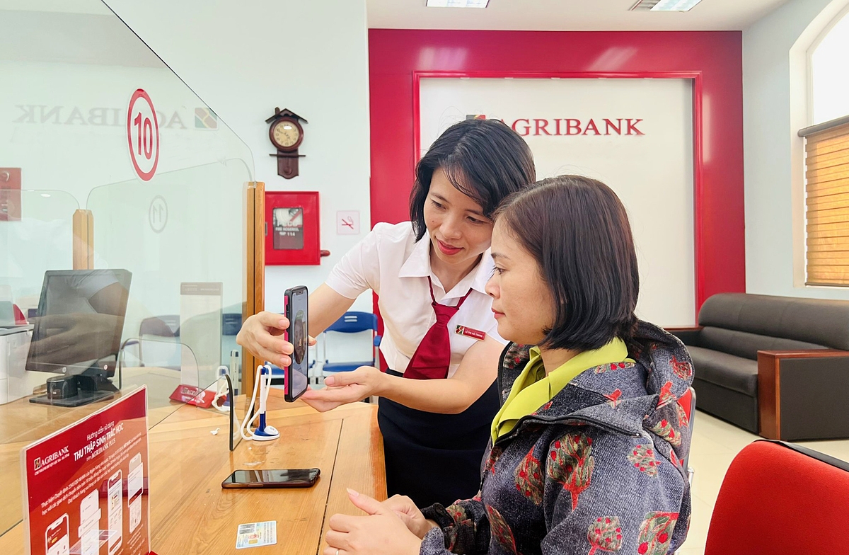 Cán bộ Agribank hỗ trợ khách hàng cập nhật sinh trắc học.