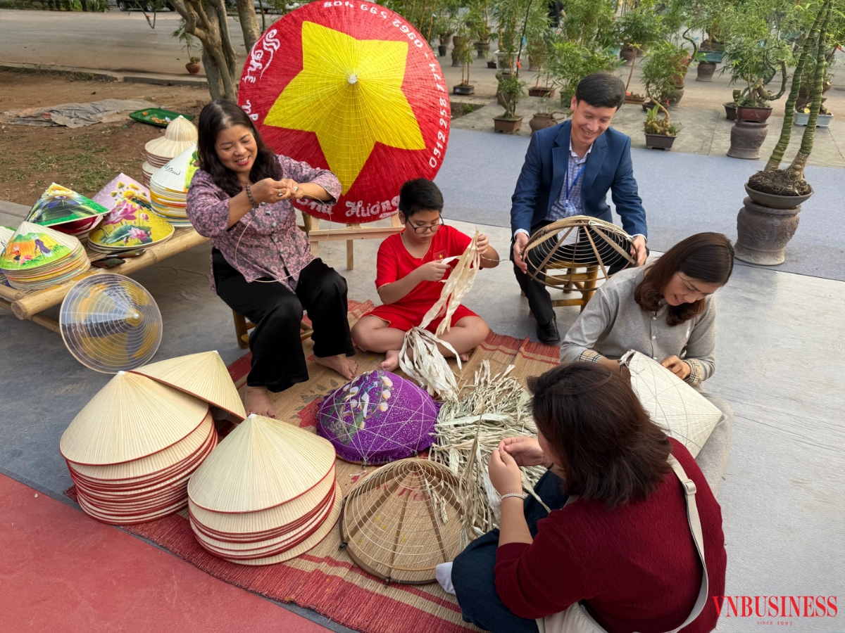 Nghệ nhân Tạ Thu Hương (áo hoa tím) đang hướng dẫn du khách làm nón.