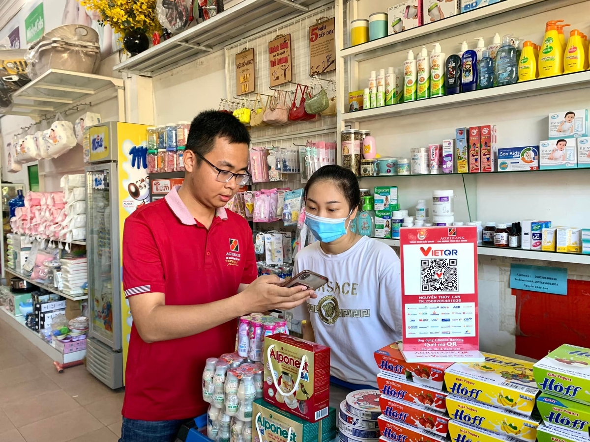 Cán bộ Agribank hướng dẫn khách hàng sử dụng dịch vụ số - nền tảng để thay đổi thói quen thanh toán bằng tiền mặt.