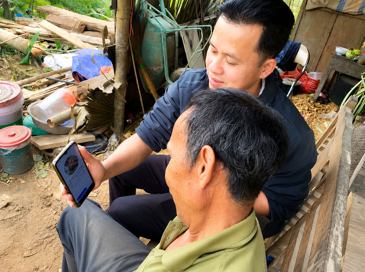 Cán bộ xã Nghĩa Tá (Chợ Đồn) hướng dẫn người dân sử dụng điện thoại thông minh - Ảnh: Thu Trang.