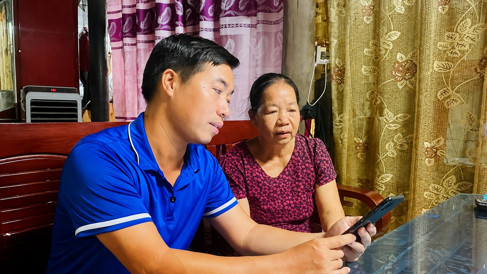 Ông Cao Tiến Viện - Trưởng thôn Tân Lợi, xã Minh Hóa - Thành viên Tổ chuyển đổi số xuống tận hộ gia đình hướng dẫn bà con cập nhập thông tin. - Ảnh: Phạm Tiến
