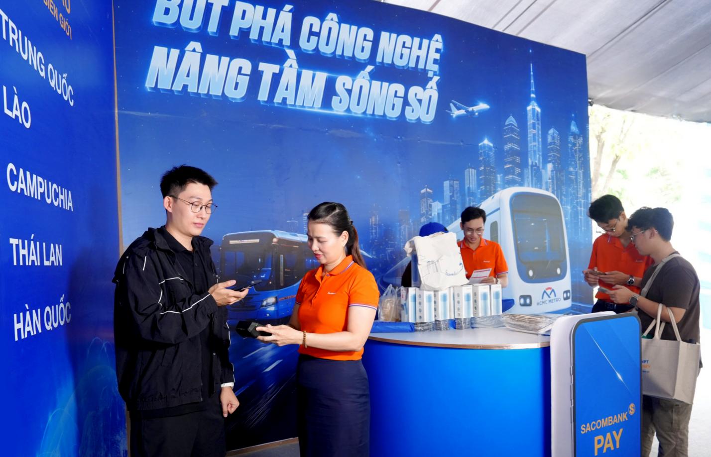 Một du khách Trung Quốc (góc trái) trải nghiệm dịch vụ thanh toán VIETQRGlobal ngay trên app Alipay tại gian hàng SACOMBANK sáng 6/6.