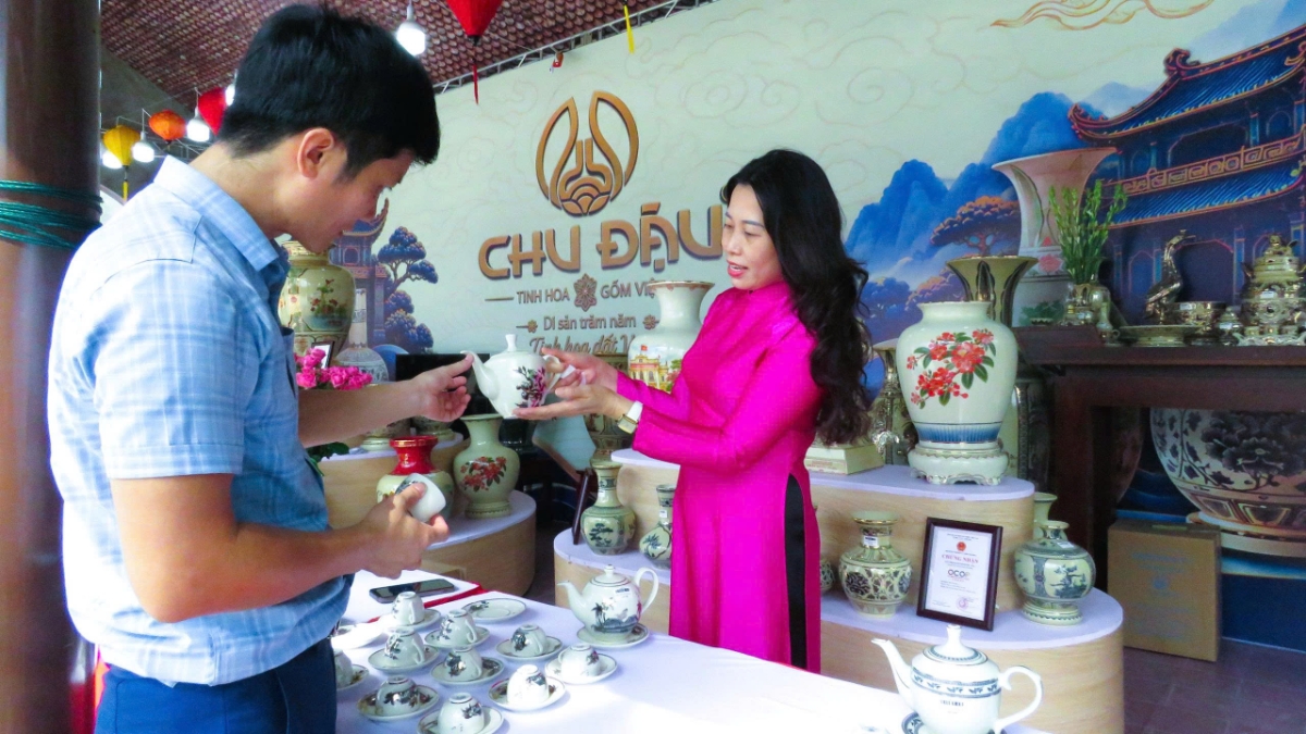 Nhân viên bán hàng tư vấn cho du khách lựa chọn sản phẩm gốm Chu Đậu. Ảnh: VT